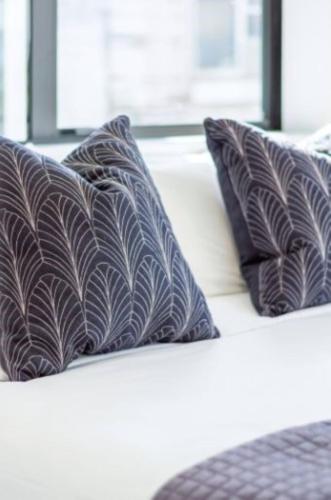 a white couch with three pillows on it at Central City Awaits 2 bed 2 bath in Christchurch
