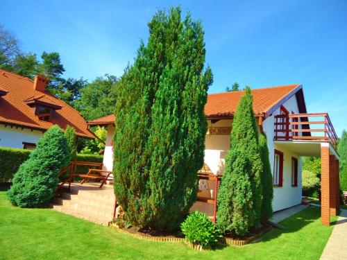 a house with two large trees in the yard at Holiday Home Kubus in Poddąbie