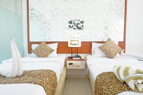 2 łóżka w pokoju hotelowym z białymi ścianami w obiekcie Samsara Inn w mieście Legian