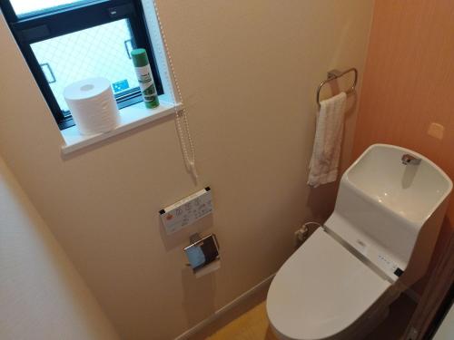 a small bathroom with a toilet and a window at IIIホーム in Shijonawate