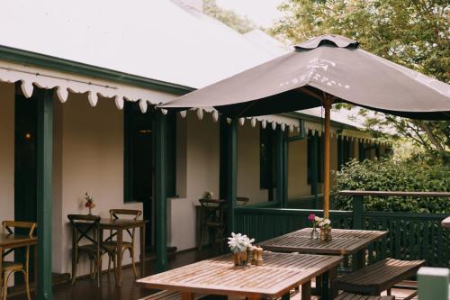 a patio with two tables and an umbrella at Flowerdale Estate in Strath Creek