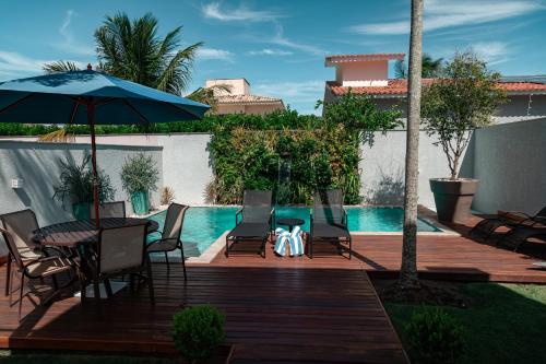 eine Terrasse mit Stühlen und einem Sonnenschirm neben einem Pool in der Unterkunft Casa de Temporada Homer House in Porto Seguro