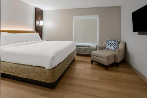 um quarto com uma cama grande e uma cadeira em The Marco Hotel Lake Charles em Lake Charles