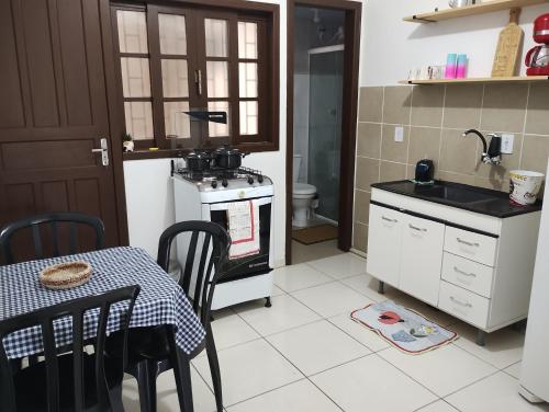 eine Küche mit einem Tisch, einer Spüle und einem Herd in der Unterkunft Casa das Embaúbas 1 in São José