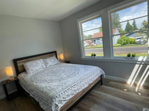 ein Schlafzimmer mit einem Bett und zwei Fenstern in der Unterkunft Modern 3 Bedroom Home in Beaverton in Beaverton