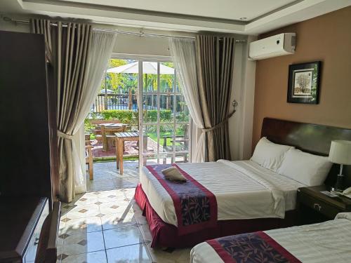 a hotel room with two beds and a balcony at Marand Resort -Highway in Bauang