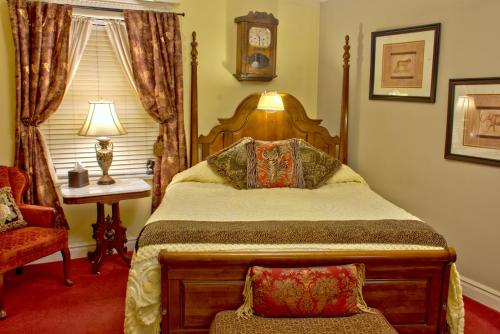 a bedroom with a bed and a chair and a clock at Big Yellow Inn in Cedar City