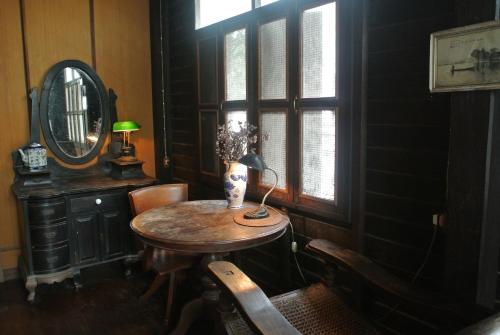 een kamer met een tafel, een spiegel en een raam bij Villa Guest House in Bangkok