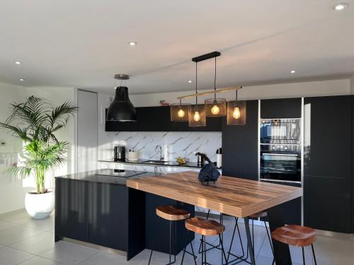 eine Küche mit schwarzen Schränken und eine Holzinsel mit Hockern in der Unterkunft Warm apartment + private free park. in Vétraz-Monthoux