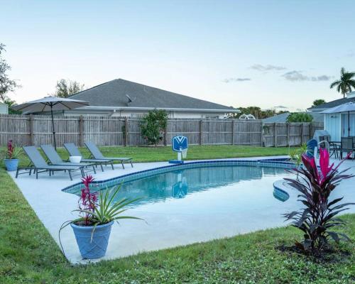 a swimming pool in a yard with chairs and flowers at Great Location, 10 Mins to Beach, Vero Pool House in Vero Beach