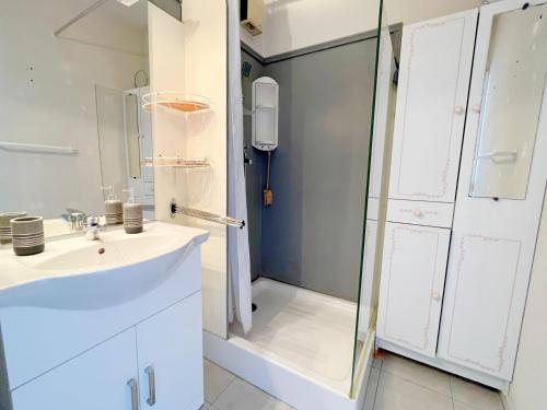 une salle de bain blanche avec une douche et un lavabo dans l'établissement Studio cabine avec piscine à Sète - FR-1-338-414, à Sète