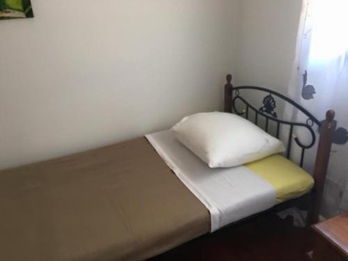 ein kleines Bett mit einem schwarzen Rahmen und einem weißen Kissen in der Unterkunft Karenga appartel Tontouta in La Tontouta