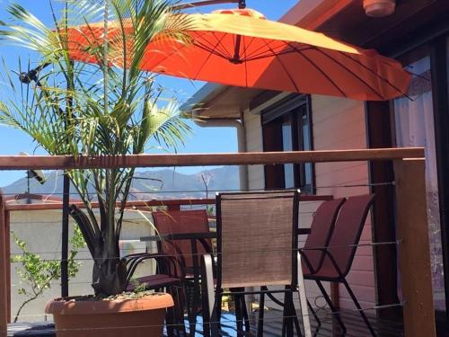 d'une table, de chaises et d'un parasol sur le balcon. dans l'établissement Karenga appartel Tontouta, à La Tontouta