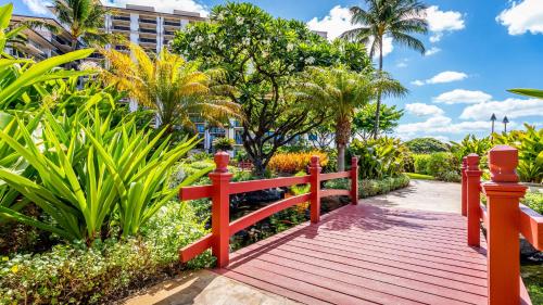 a red bridge in a park with trees and plants at Ko Olina Beach Villas O401 in Kapolei