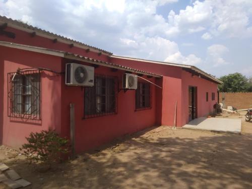 a red building with two windows and aliction at Casa San José in San José de Chiquitos