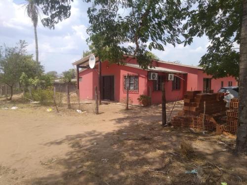 a red house with a fence in front of it at Casa San José in San José de Chiquitos