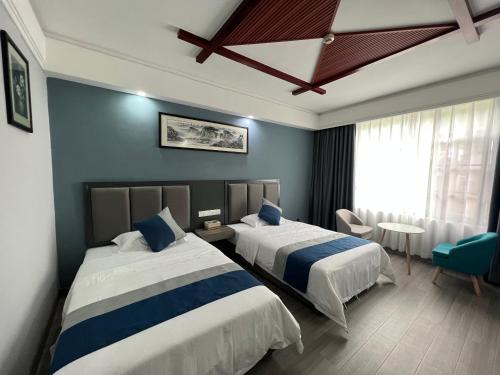 Habitación de hotel con 2 camas y mesa en 张家界喜见客栈 en Zhangjiajie