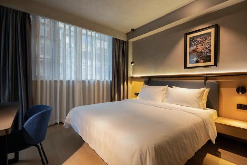 成都市にあるChengdu Desti Youth Park Hostel TaiKooLiの大きなベッドと机があるホテルの部屋