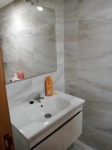 a white bathroom with a sink and a mirror at Family Vacation Apartment- VacayX- Temara in Temara