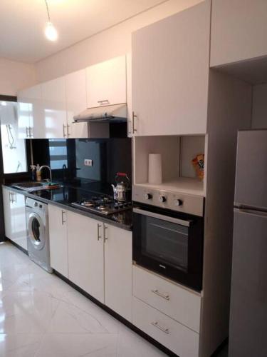 cocina con armarios blancos y fogones en Family Vacation Apartment- VacayX- Temara, en Temara