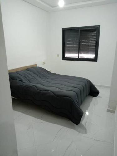 a bed in a white room with a black blanket at Family Vacation Apartment- VacayX- Temara in Temara