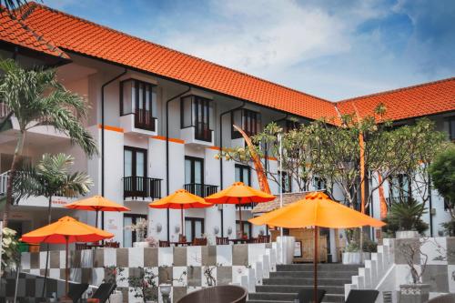 uma vista exterior de um hotel com guarda-sóis laranja em HARRIS Hotel Kuta Tuban Bali em Kuta