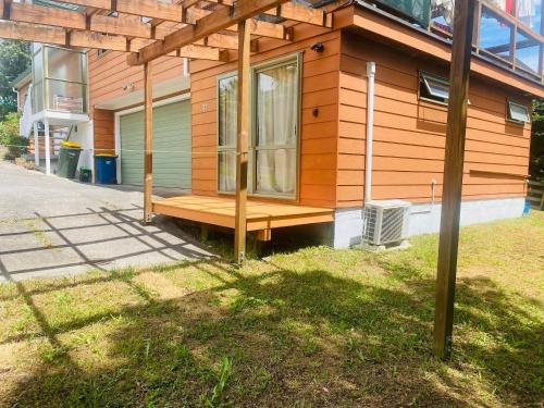 a house with a wooden porch with a window at Private studio Auckland Self Checkin and 2 Parking Netflix Prime in Auckland