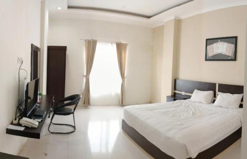 a bedroom with a bed and a chair and a television at KHARIZ HOTEL in Bukittinggi