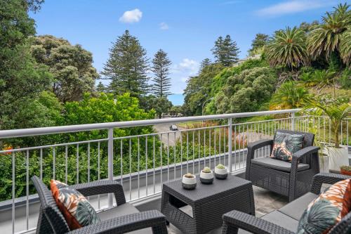 a balcony with chairs and a table and trees at Hillcrest Hideaway - Napier Holiday Apartment in Napier