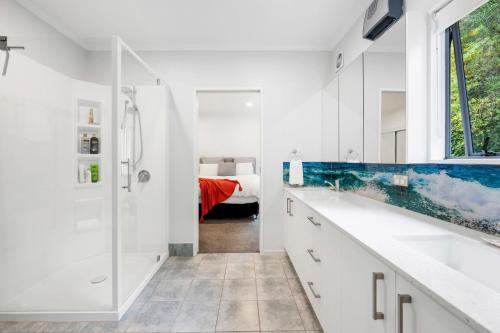 a white bathroom with a shower and a sink at Hillcrest Hideaway - Napier Holiday Apartment in Napier