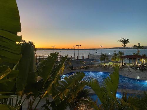 a resort with a pool and a beach at sunset at Flat central em brasilia in Brasilia