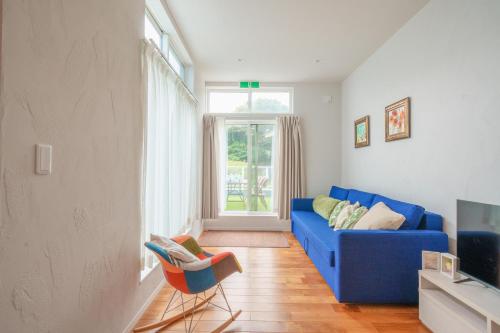 a living room with a blue couch and a window at Beachside base KURUWA in Yokosuka