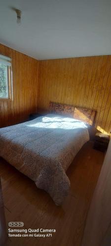 een slaapkamer met een bed in een houten muur bij Cabañas piedra azul in Puerto Montt
