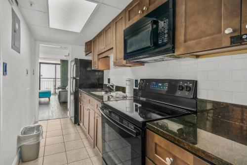 a kitchen with a stove and a sink and a microwave at 441 Landmark Resort in Myrtle Beach