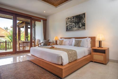 a bedroom with a large bed and a balcony at Budhi Ayu Villas and Cottages Ubud by Mahaputra-CHSE Certified in Ubud