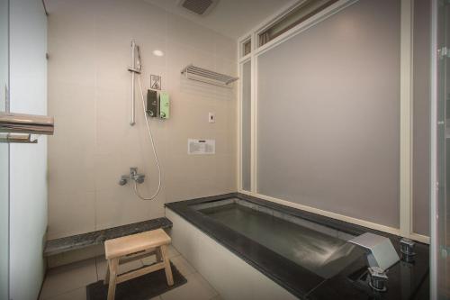 a bathroom with a bath tub with a wooden stool at New Taipei Hot Spring Hotel in Xindian