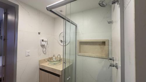 a bathroom with a glass shower with a sink at Flat central em brasilia in Brasilia