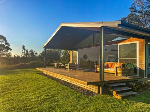 a house with a wooden deck in the grass at Pindara in Broke