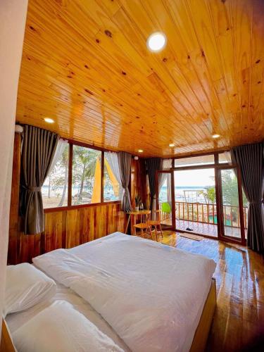 a bedroom with a large bed in a room with windows at Bai Thom Retreat in Phú Quốc