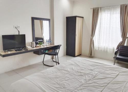 una camera con letto, scrivania e specchio di KHARIZ HOTEL a Bukittinggi