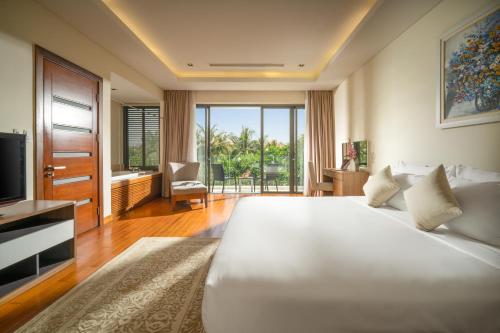 a bedroom with a large white bed and a television at Blue Ocean Villas Danang in Danang