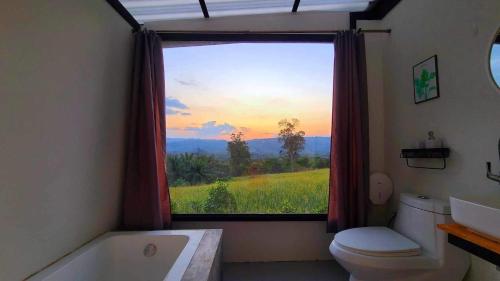 a bathroom with a window with a view of a field at Heaven Hill Camping in Ban Thung Na