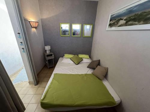 Cette petite chambre comprend un lit avec des draps et des oreillers verts. dans l'établissement T2 à Valras-Plage, 4 pers, à 30m de la plage, parking privé, cuisine équipée - FR-1-701-74, à Valras-Plage