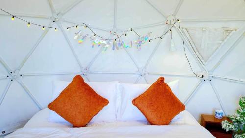 a bed with orange pillows and a string of lights at Heaven Hill Camping in Ban Thung Na