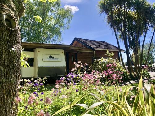 a house with a garden with flowers in front of it at Unique and Charming Garden Cottage/Campervan in Rangataua