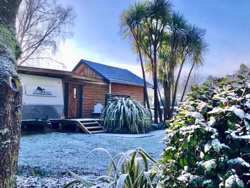 a house with a trailer parked in front of it at Unique and Charming Garden Cottage/Campervan in Rangataua