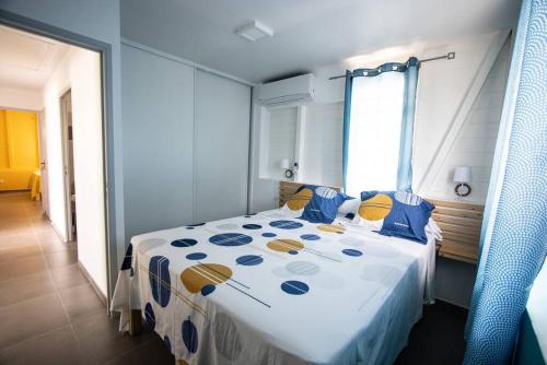 Schlafzimmer mit einem Bett mit blauen und gelben Kissen in der Unterkunft Séjour Glycéria: Villa Canne à Sucre in Le Marin