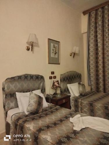 una habitación de hotel con 2 camas y una silla en Anubis Hostel en El Cairo