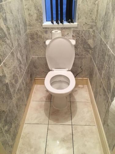 a bathroom with a white toilet in a tiled room at Liverpool Recently Refurbished Spacious House in Liverpool