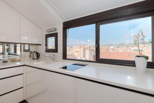 une cuisine avec des placards blancs et une grande fenêtre dans l'établissement Wonderful studio heart of Cannes!!, à Cannes